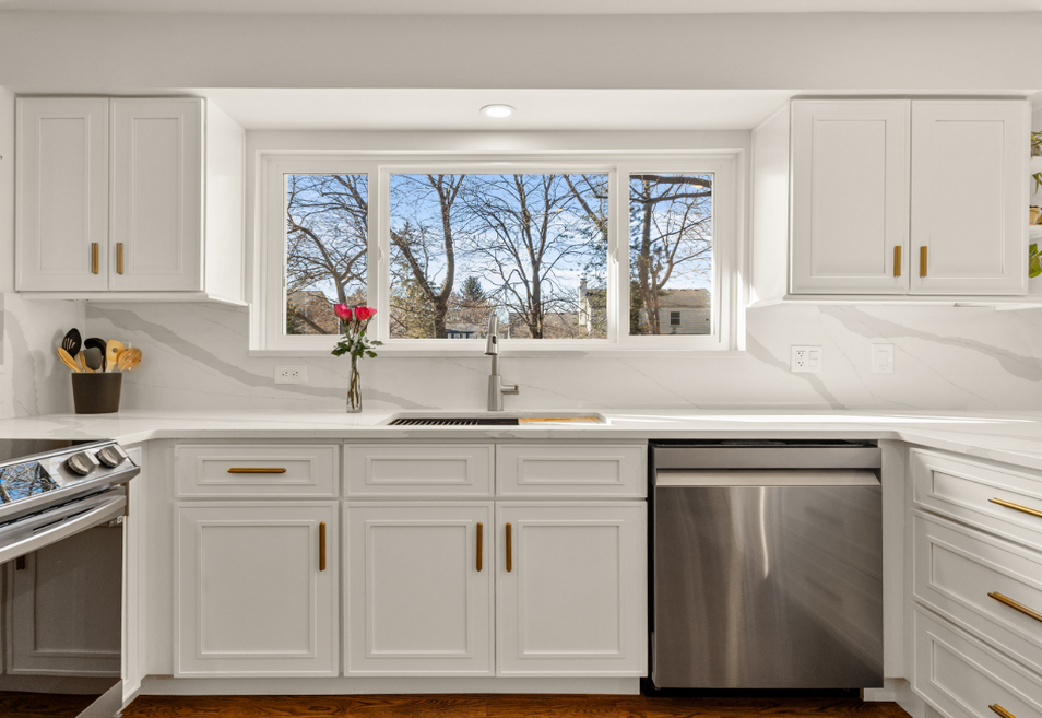Modern kitchen featuring Ava Cabinetry Craftsman White shaker cabinets, gold hardware, and white marble-patterned countertops with a stainless steel dishwasher.
